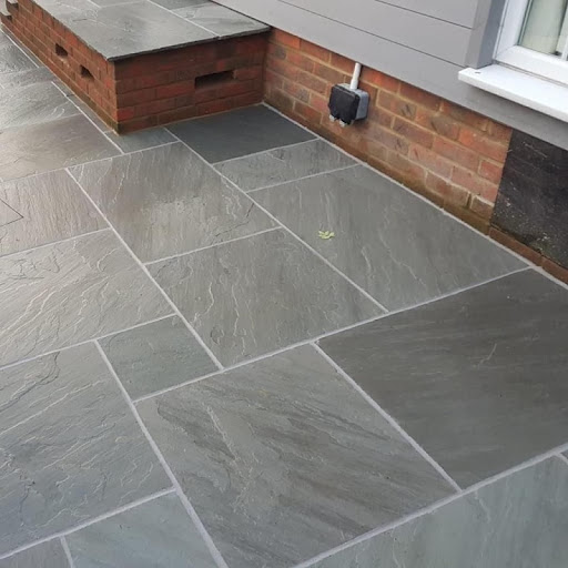 Completed grey natural sandstone paving detail beside a property by Harcourt Exteriors